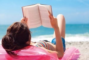 砂浜に寝転んで本を読んでいる女性の画像.jpg